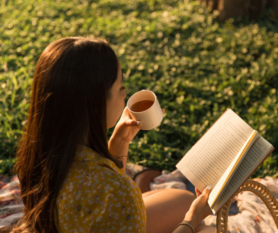 Woman reading a book in a park and sipping a cup of tea