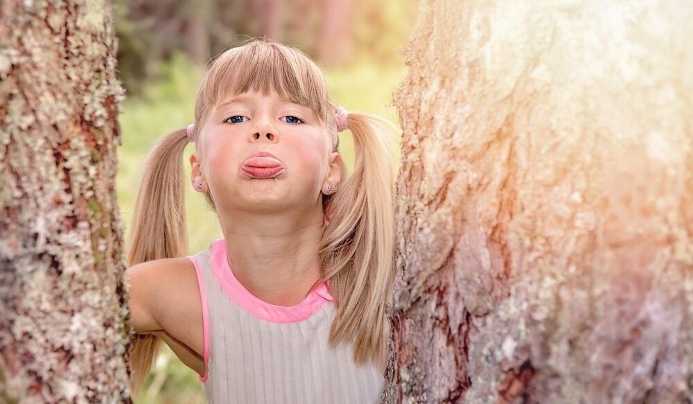 Little girl sticking her tongue out between two trees