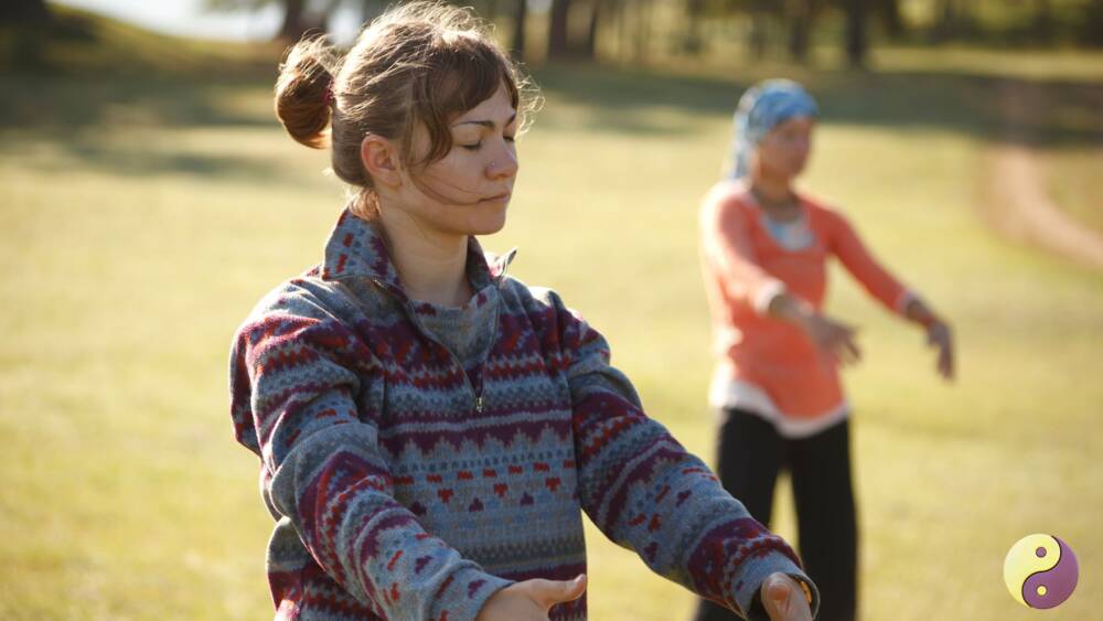 dos mujeres que practican qigong estatico en un parque