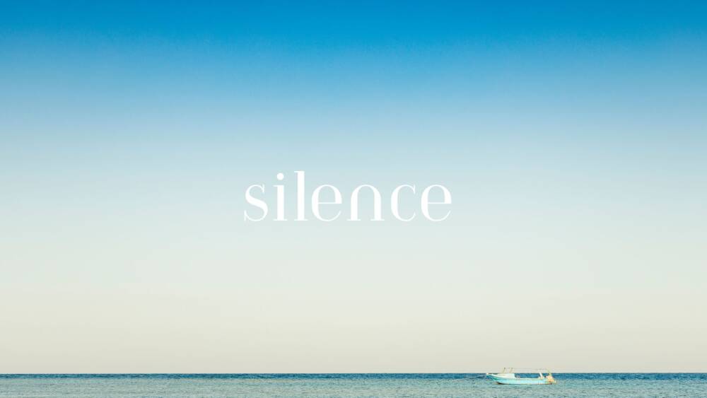 a solitary boat and a blue sky, the word silence appears in the sky